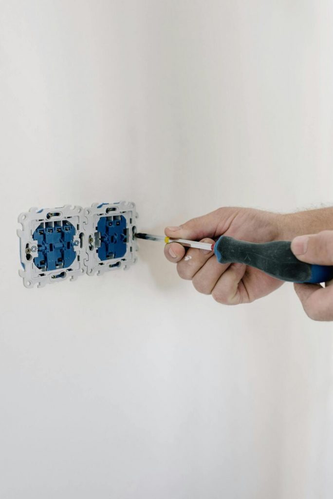 Person installing something into a wall with a screwdriver